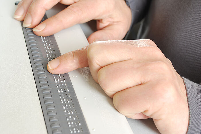 Person verwendet einen Braille-Tastatur