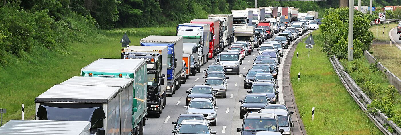 Stau auf einer dreispurigen Autobahn, linke Spur LKWs, mittlere und rechte Spur PKWs