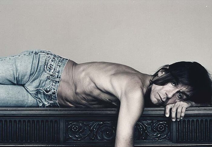 Iggy Pop liegend nur mit Jeans bekleidet.