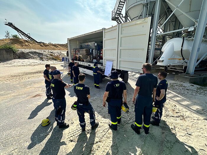 Mehrere Einsatzkräfte vor einer Sandsackfüllanlage.