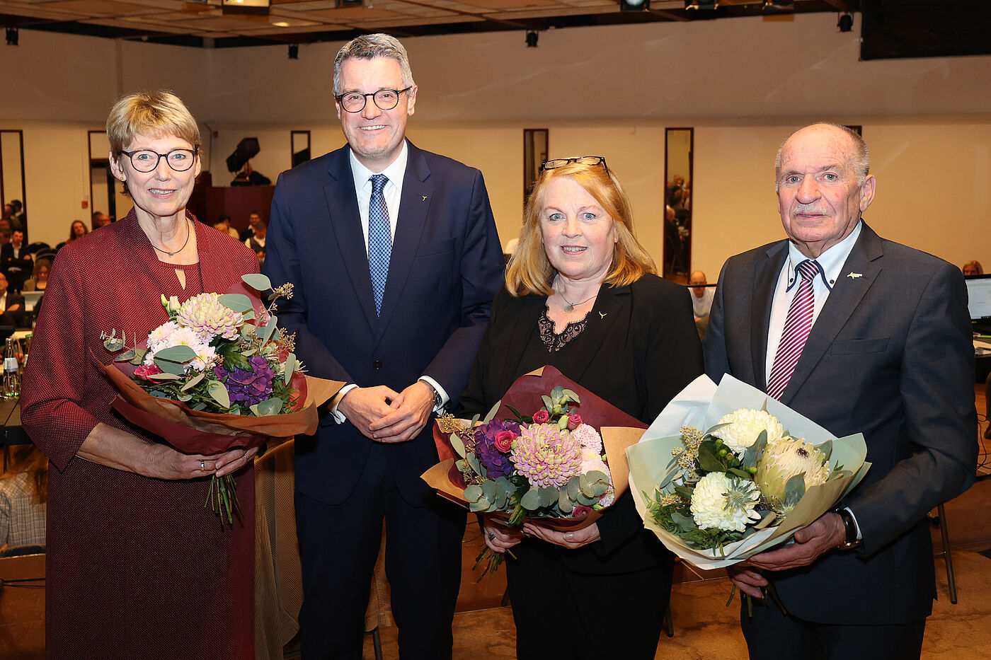 Zwei Frauen und zwei Männer mit Blumensträußen.