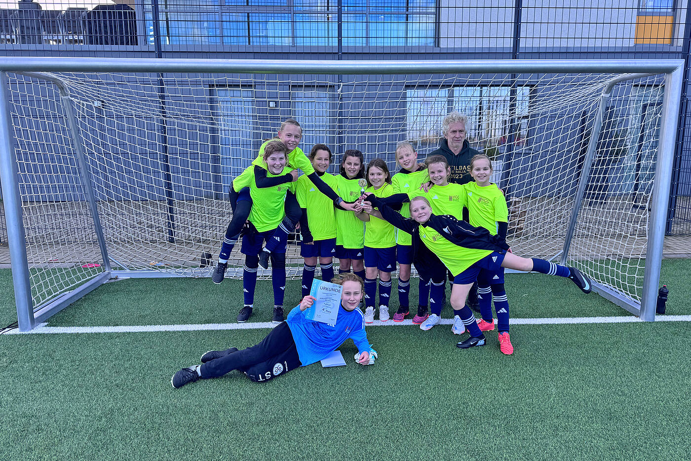 Junge Fußballerinnen posieren in einem Tor.