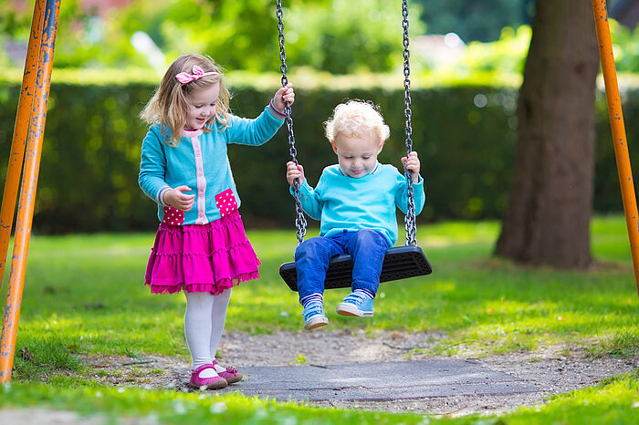 Schwester stößt ihren Bruder beim Schaukeln an