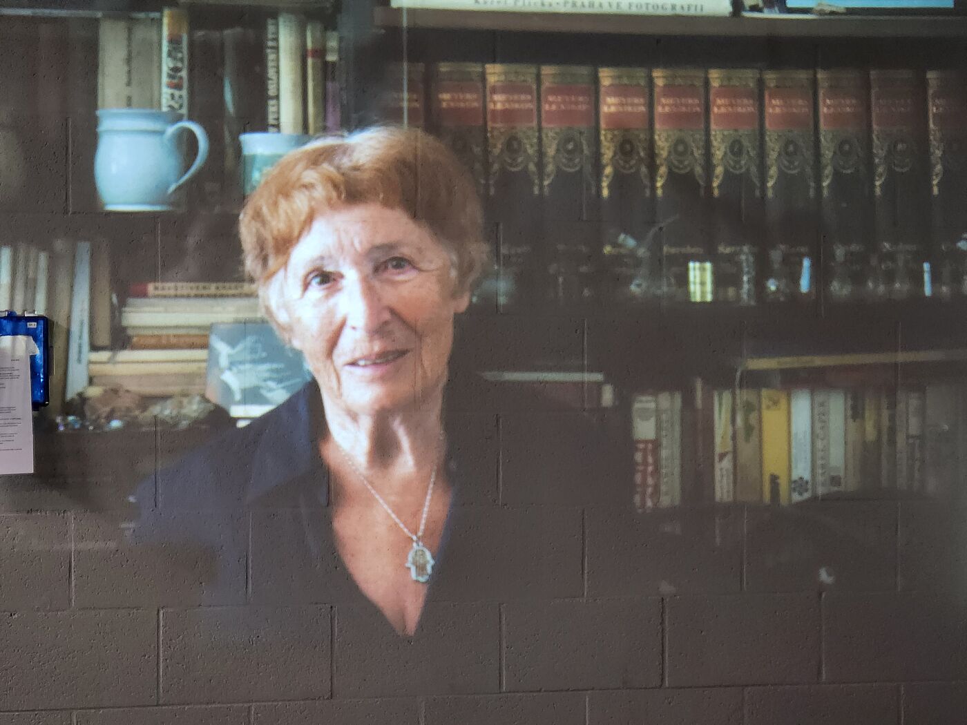 Eine ältere Frau vor einem Bücherregal.
