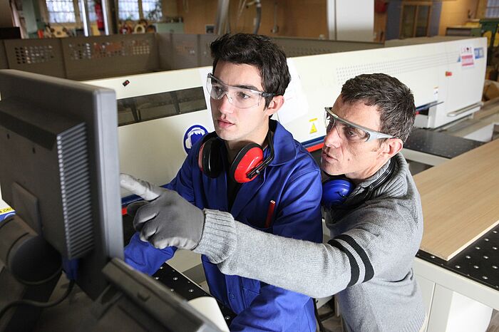 Ausbilder und Auszubildender in einer technischen Werkstatt