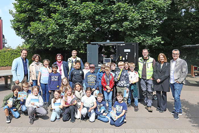 Kinder und Erwachsene vor einer Blitzanlage auf einem Schulhof.