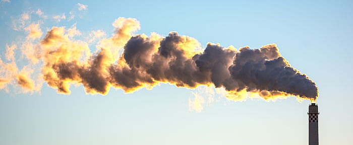 Schornstein mit einer gelben, grauen Wolkenfahne. Luftverschmutzung durch Abgase der Industrie.