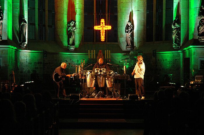 Farblich beleuchteter Altar mit drei Musikern