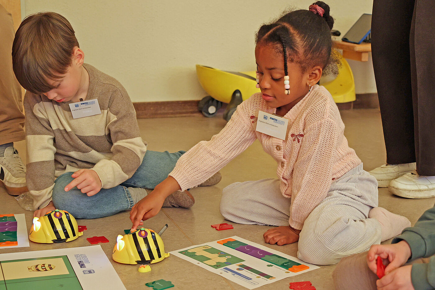 Zwei Kinder spielen mit Roboter-Bienen.