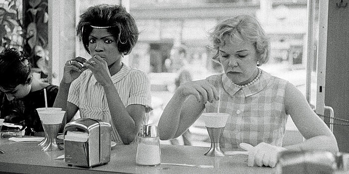 Foto von Bruce Davidson. Eine farbige und eine weisse Frau sitzen in einer Bar in New York, 1962