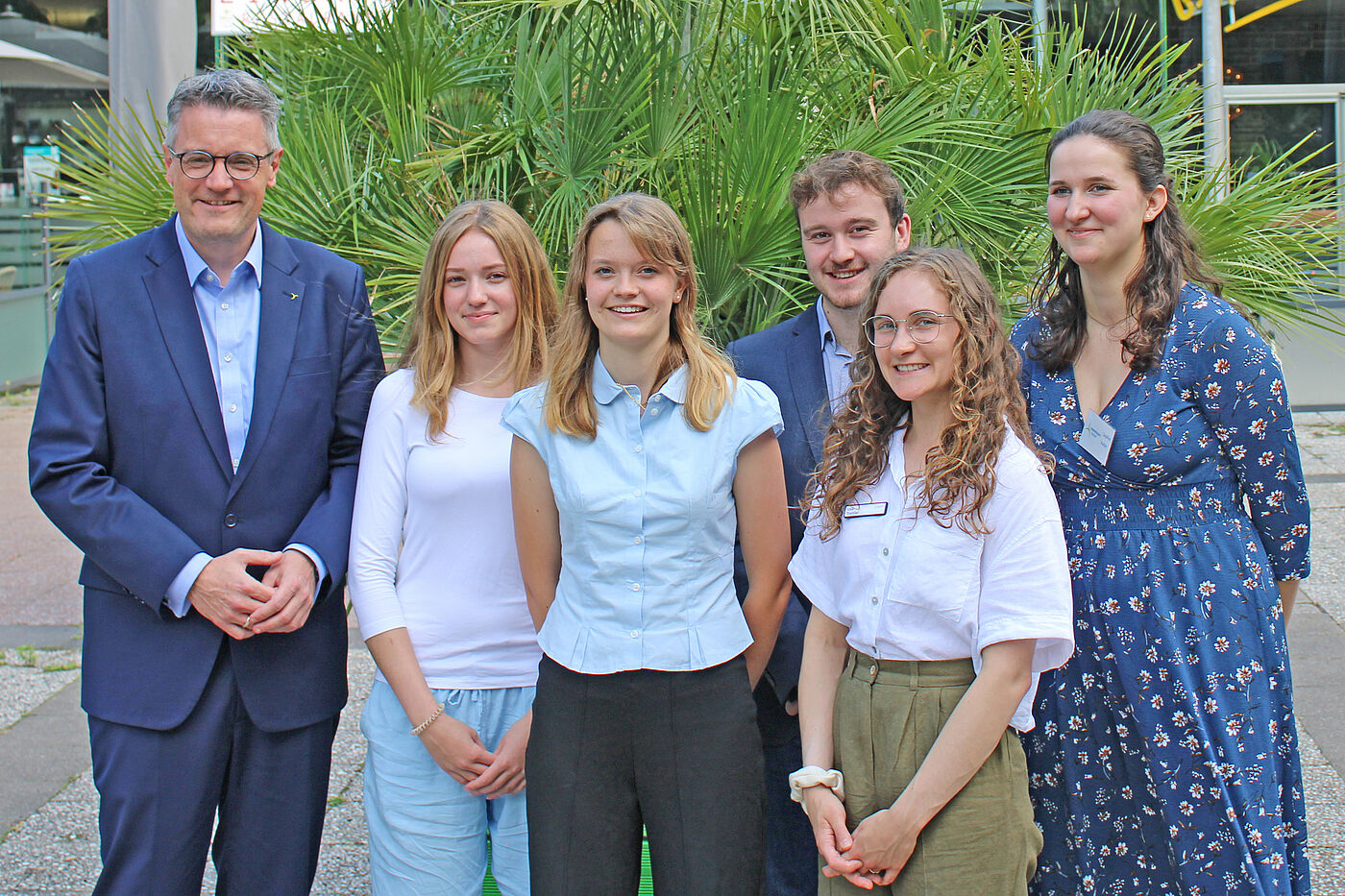 Sechs Leute stehen vor einem Busch.