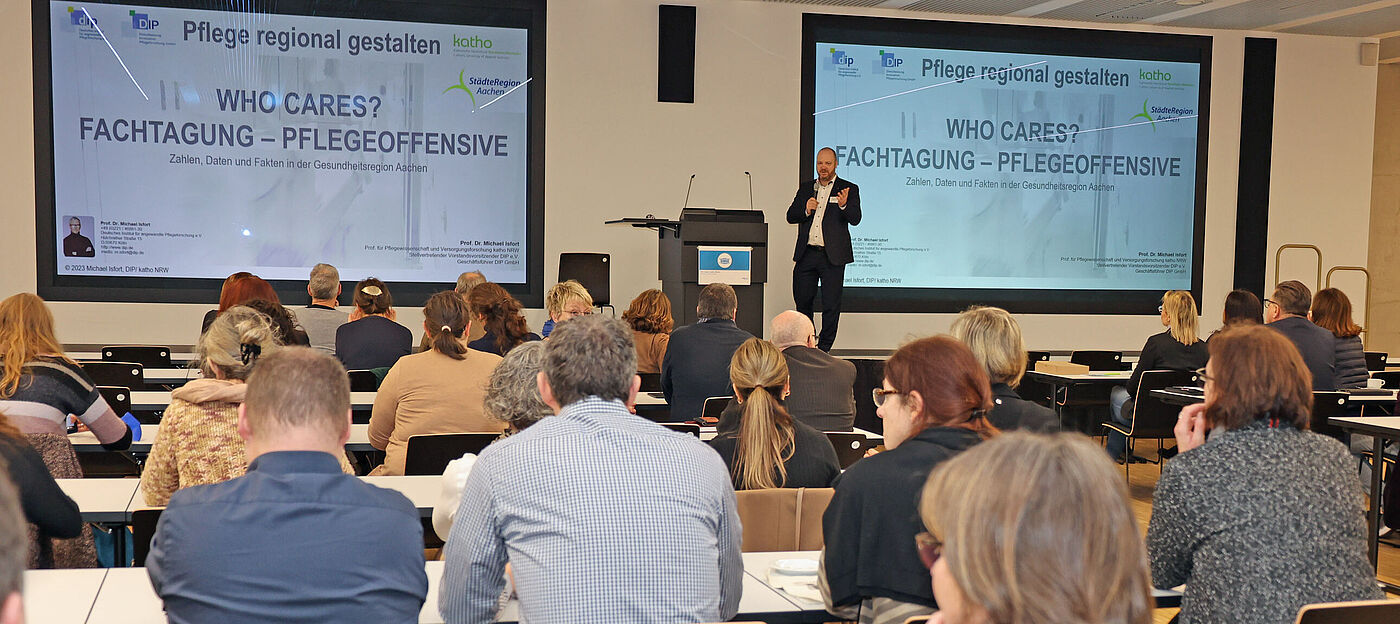 Dr. Michael Ziemons eröffnet die Fachtagung. Im Publikum sitzen viele Menschen.