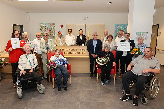 Ein Gruppenbild mit mehreren Menschen in einem Altenheim vor der Rezeption.