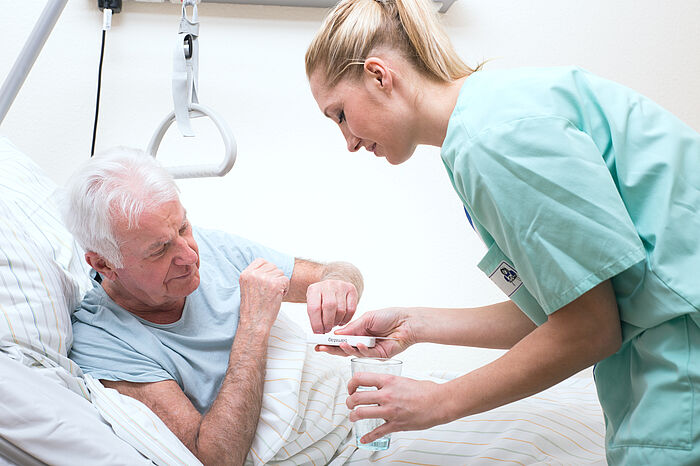 Älterer Mann im Pflegeheim wird durch eine Pflegerin betreut