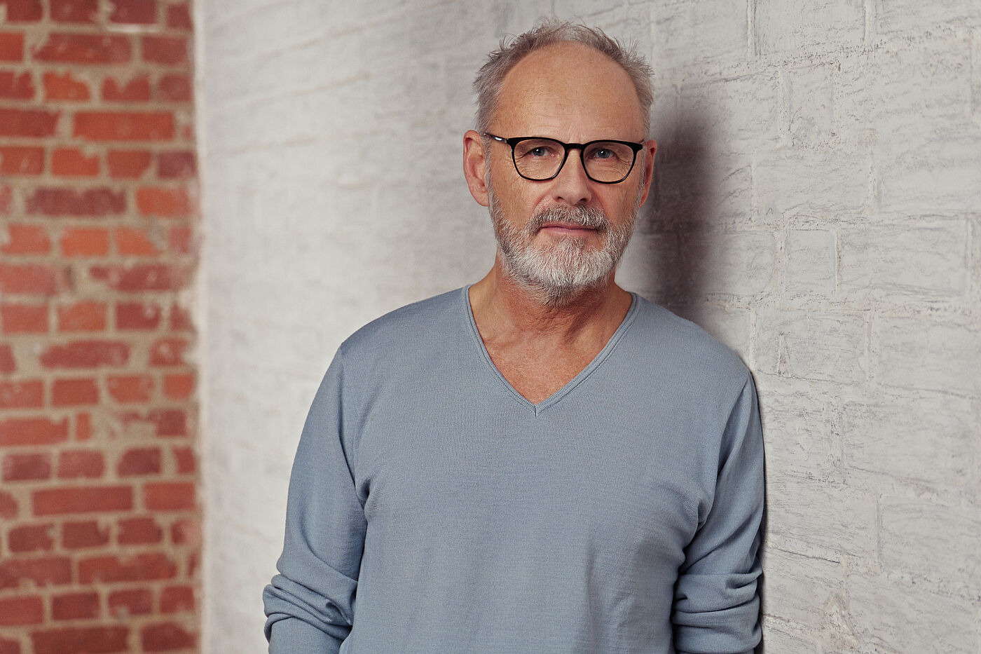 Der Moderator Reinhold Beckmann vor einer Wand. Er trägt eine Brille