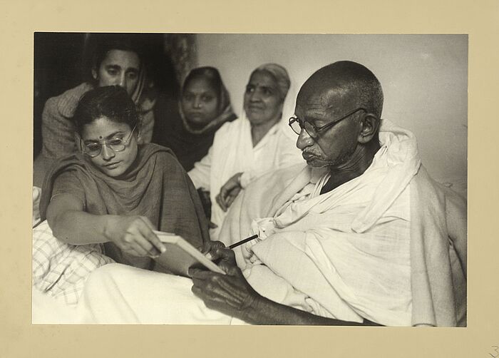Gandhi kurz vor Beendigung des Fastens von vier Personen umringt.