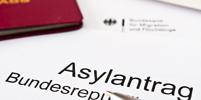 Asylantrag auf Papier mit einem Teil von einem ausländischen Pass