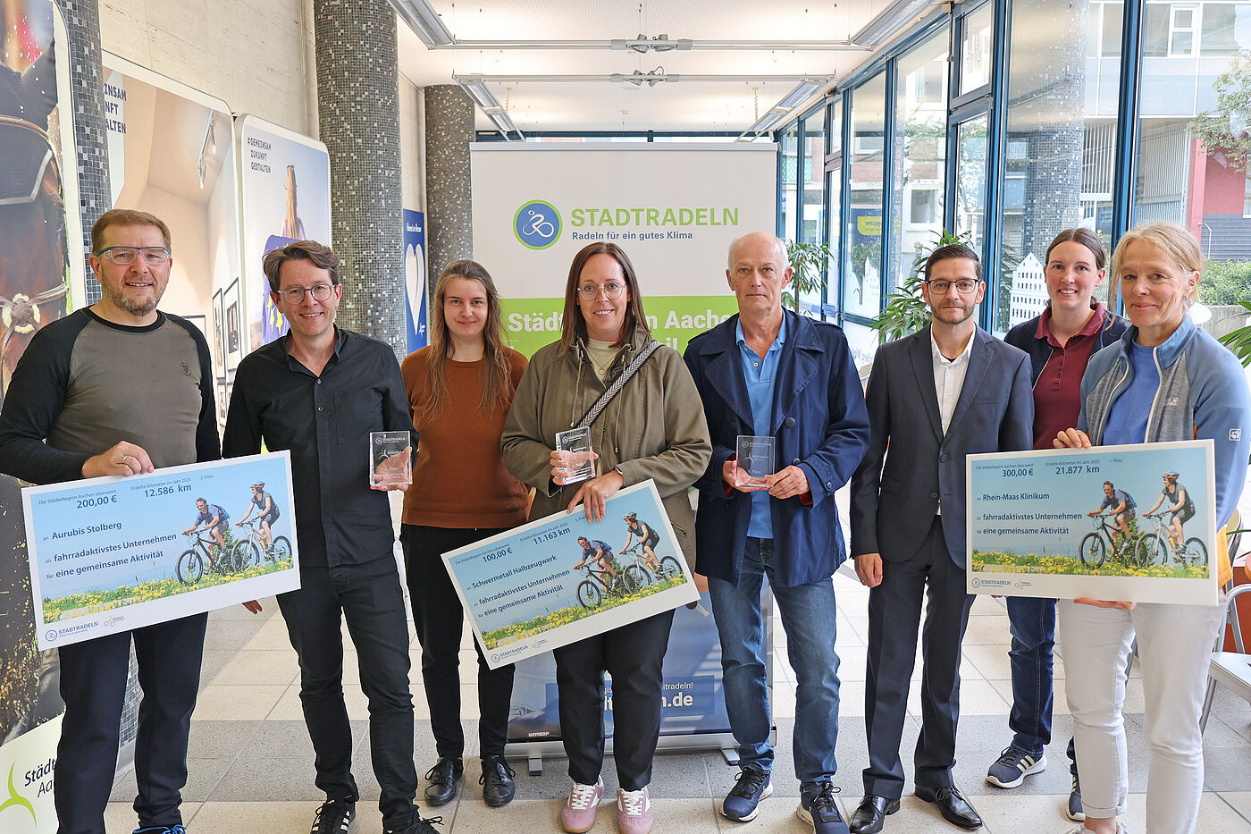 Vier Männer und vier Frauen mit großen Schecks in der Hand.