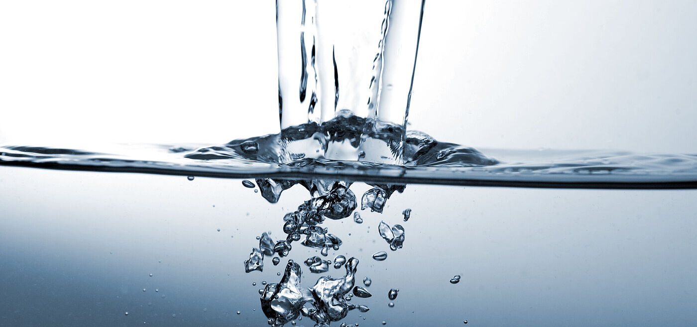 Ein Wasserstrahl trifft in eine Wasseroberfläche