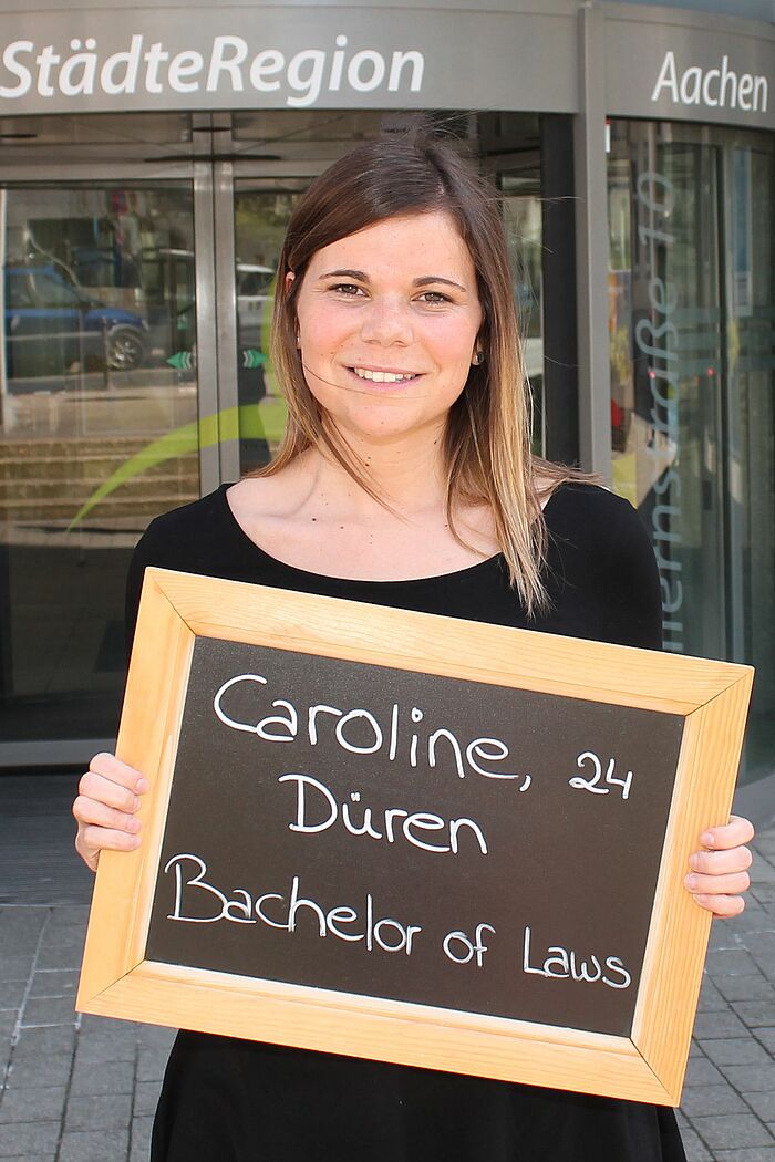 Caroline Lövenich hält Tafel mit ihrem Namen, ihrem Alter und ihrem Ausbildungsberuf