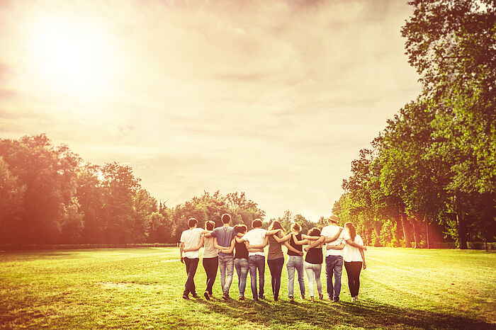Eine Gruppe von Jugendlichen geht gemeinsam durch einen sonnigen Park