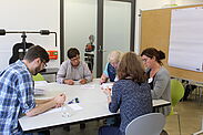 Workshopteilnehmende sitzen an einem Tisch und arbeiten.