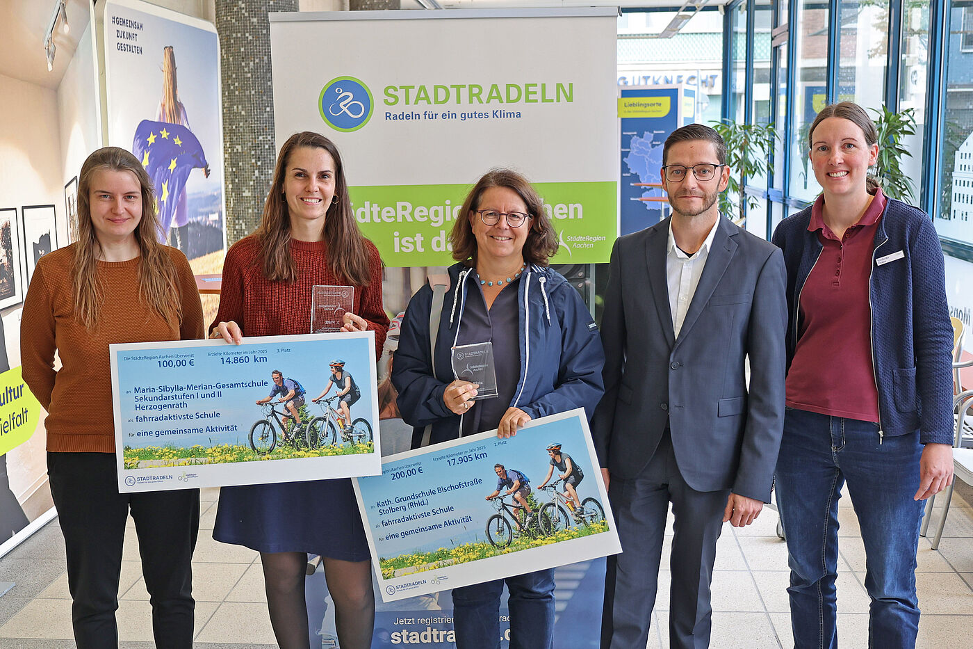 Vier Frauen und ein Mann mit großen Schecks in der Hand.