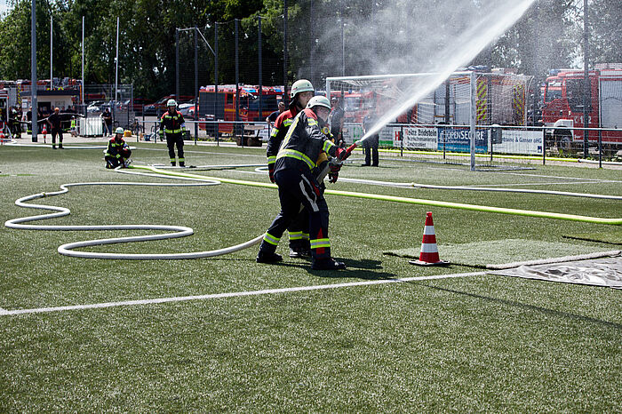 Feuerwehrleute bei einer Übung auf einem Sportplatz.