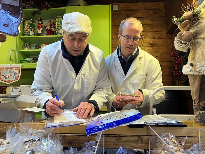 Stefan Schnitzler und Dr. Mathias Boese tüten ein Lebkuchenherz ein. Die Probe wird im Labor auf ihre Inhaltsstoffe untersucht.