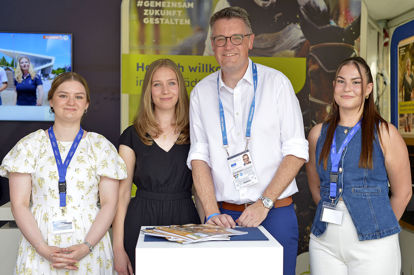 Ein Mann und drei Frauen an einem Messe-Stand.