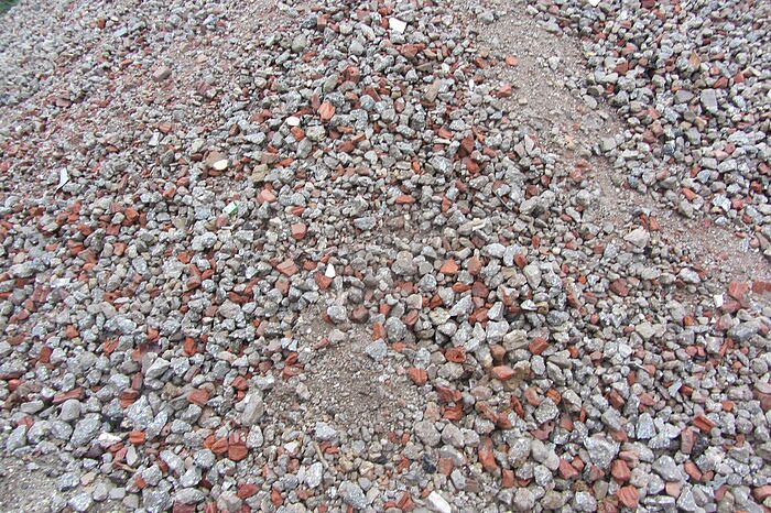 Aufnahme von Recyclingmaterila. Zu sehen sind Steinbruchstücke in verschiednen Größen, mit Ziegelbruchstücken.