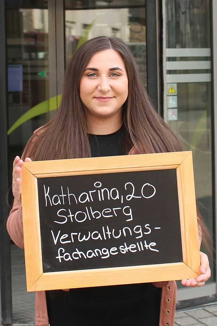 Katharina Voultsini hält Tafel mit ihrem Namen, ihrem Alter und ihrem Ausbildungsberuf