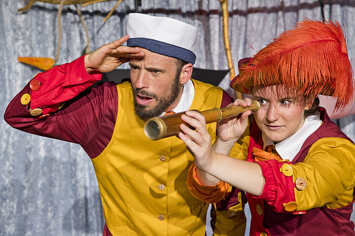 Die Figuren Schnick und Schnack schauen gemeinsam mit einem Fernrohr in die Ferne