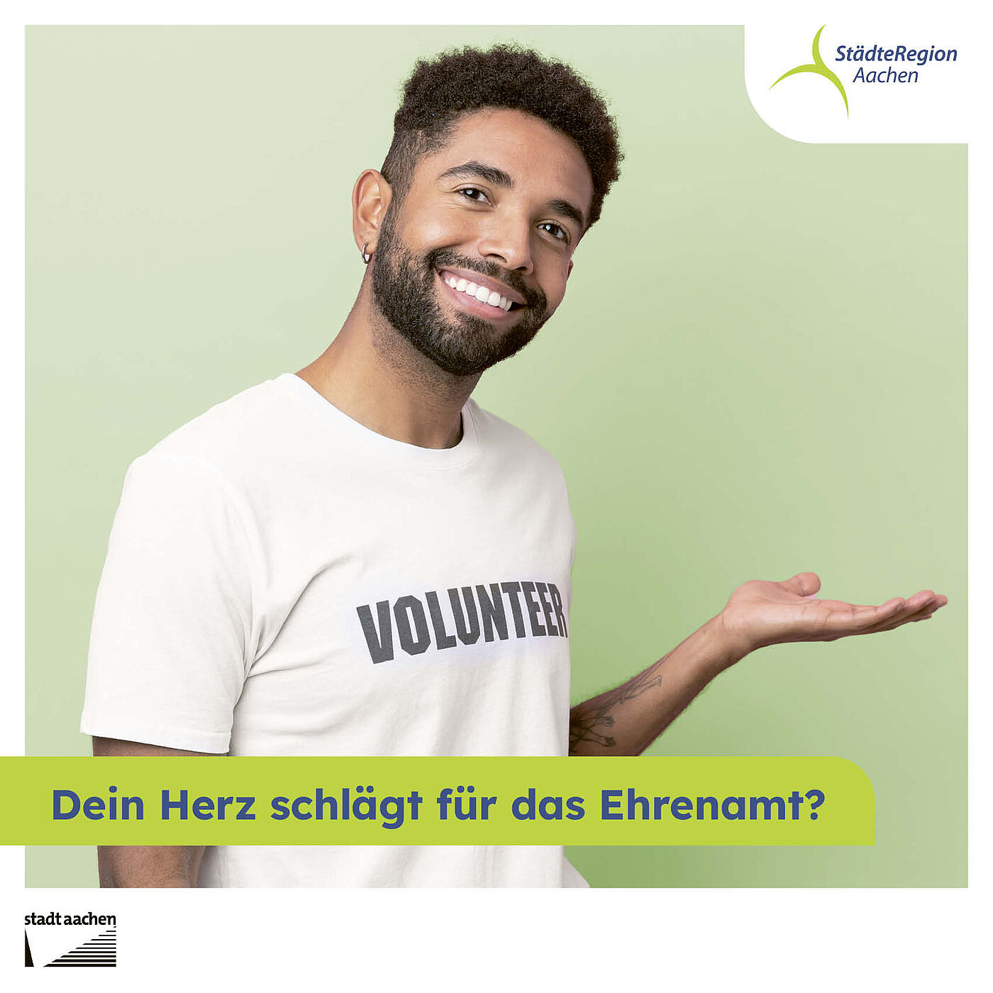 Ein junger Mann weist lächelnd auf das Ehrenamtsstipendium hin