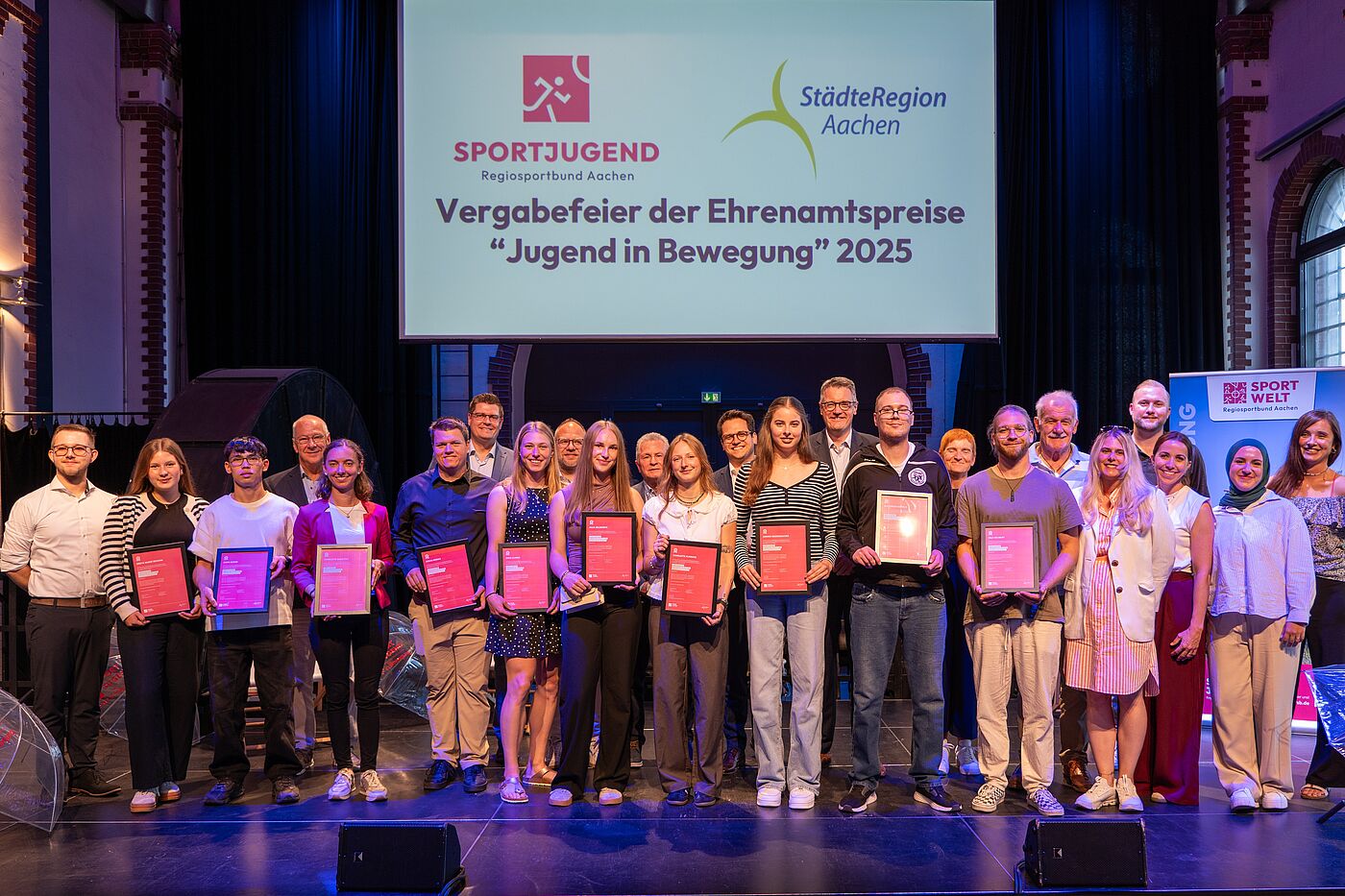 Viele junge Menschen mit Urkunden auf einer Bühne.