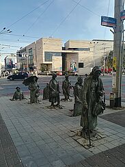 Denkmal: Eine Gruppe von lebensgroßer menschlicher Figuren, die sich aus dem Bürgersteig heraus erheben