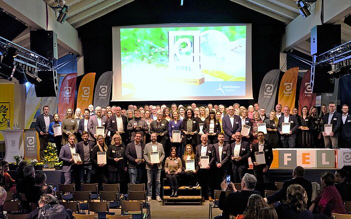 Alle Preisträger des EIFEL Awards stehen auf einer Bühne und halten ihre Urkunden in den Händen.