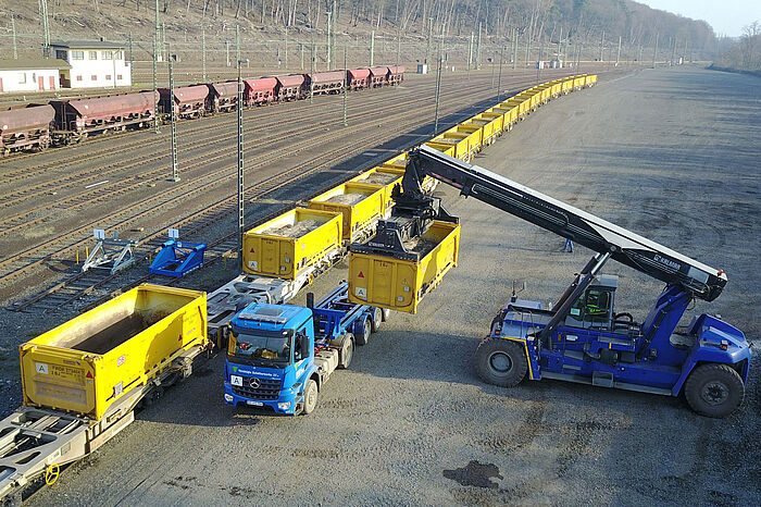 Ein Reachstacker, das ist eine Art Bagger, bewegt einen Container von einem LKW auf einen Waggon