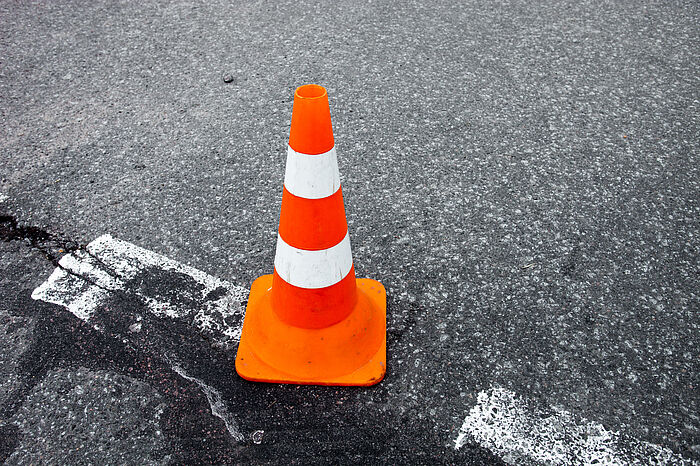 Verkehrsabsperrkegel auf defektem Asphalt