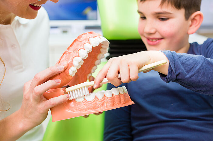 Zahnärztin erklärt Jungen richtiges Zähneputzen