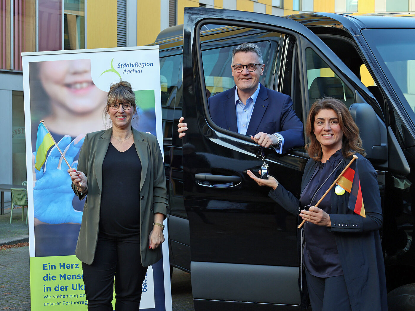 Die StädteRegion Aachen unterstützt die ukrainische Partnerregion Lwiw unter anderem mit einem Fahrzeug für den Transport von Menschen mit Behinderung: Städteregionsrat Dr. Tim Grüttemeier und Susanne Lauffs von der Stabsstelle für Strukturentwicklung, Tourismus, Europa und Ehrenamt (links) überreichten der Vorsitzenden des Blau-Gelben Kreuz, Linda Mai, symbolisch die Fahrzeugschlüssel. 