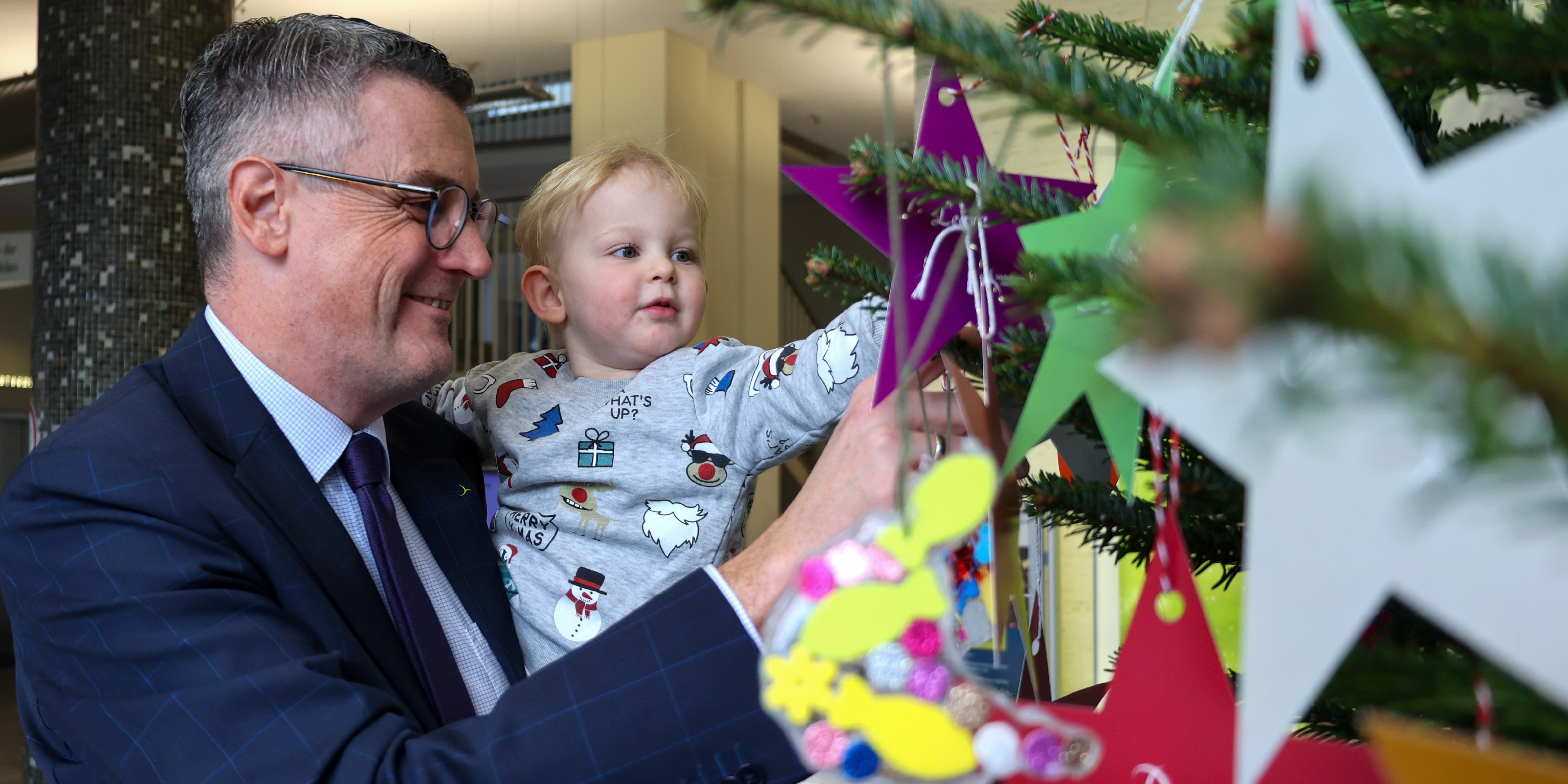 Ein Kind und ein Mann schmücken einen Weihnachtsbaum.