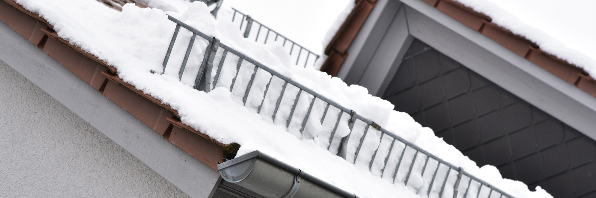 Sicherung gegen Dachlawinen an einem schneebedeckten Haus