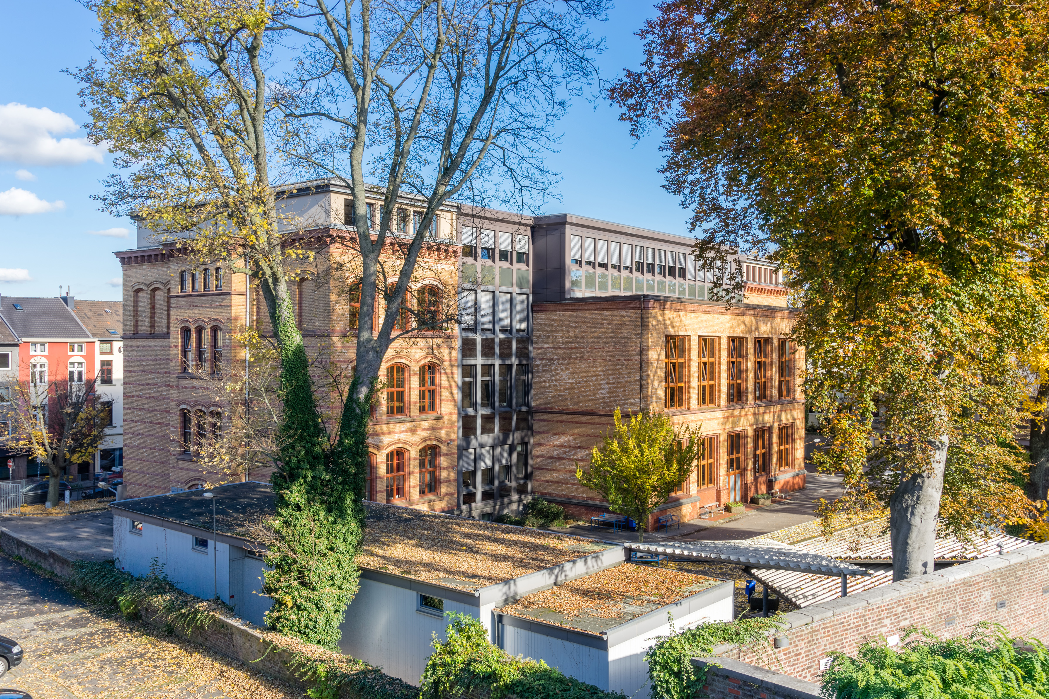 Außenansicht des Schulgebäudes des Berufskollegs für Wirtschaft und Verwaltung in Aachen von einer Anhöhe aus. Dargestellt ist die Rückansicht mit Schulhof.