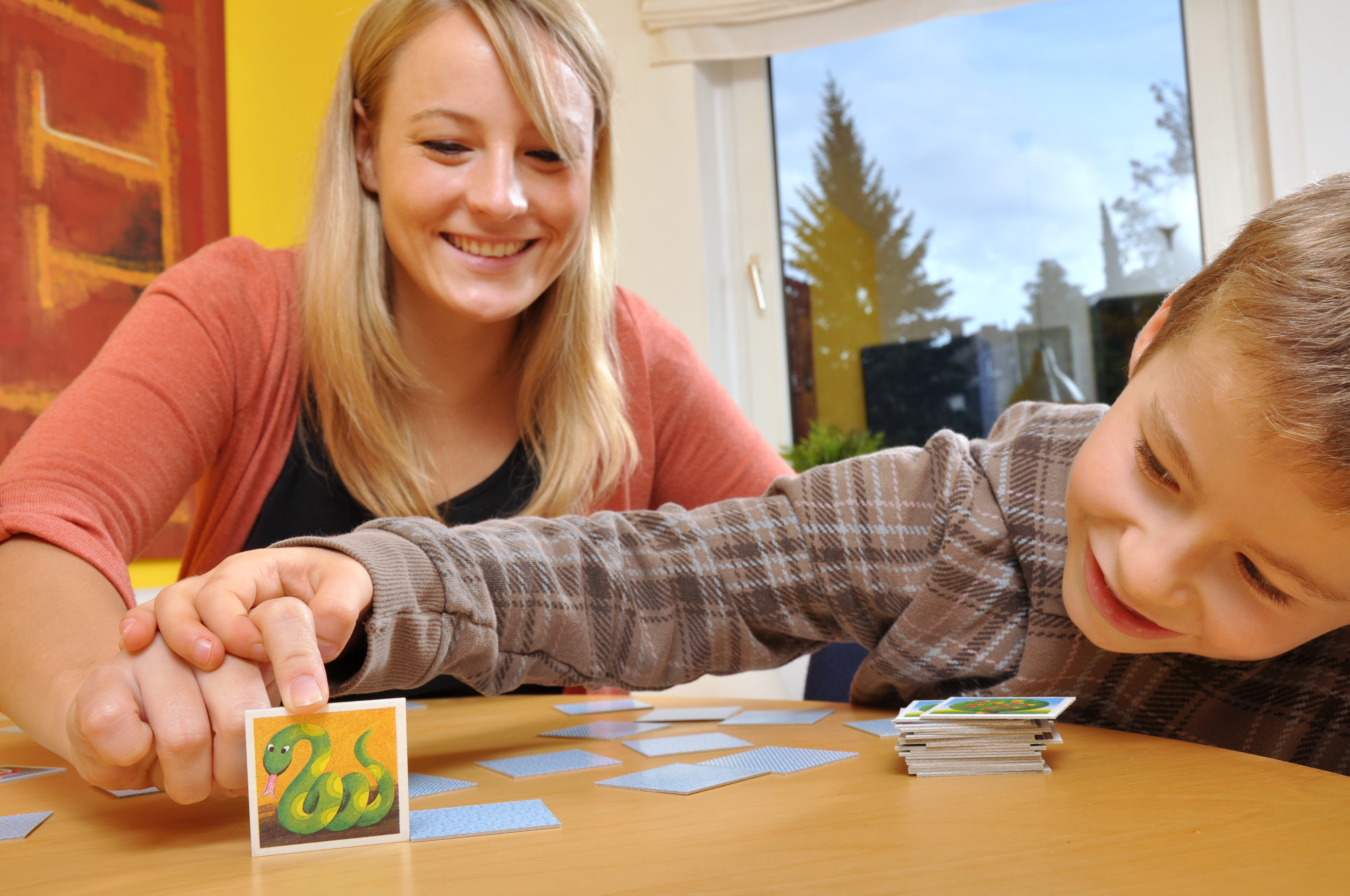 ein kleiner Junge spielt Memory mit einer Erzieherin