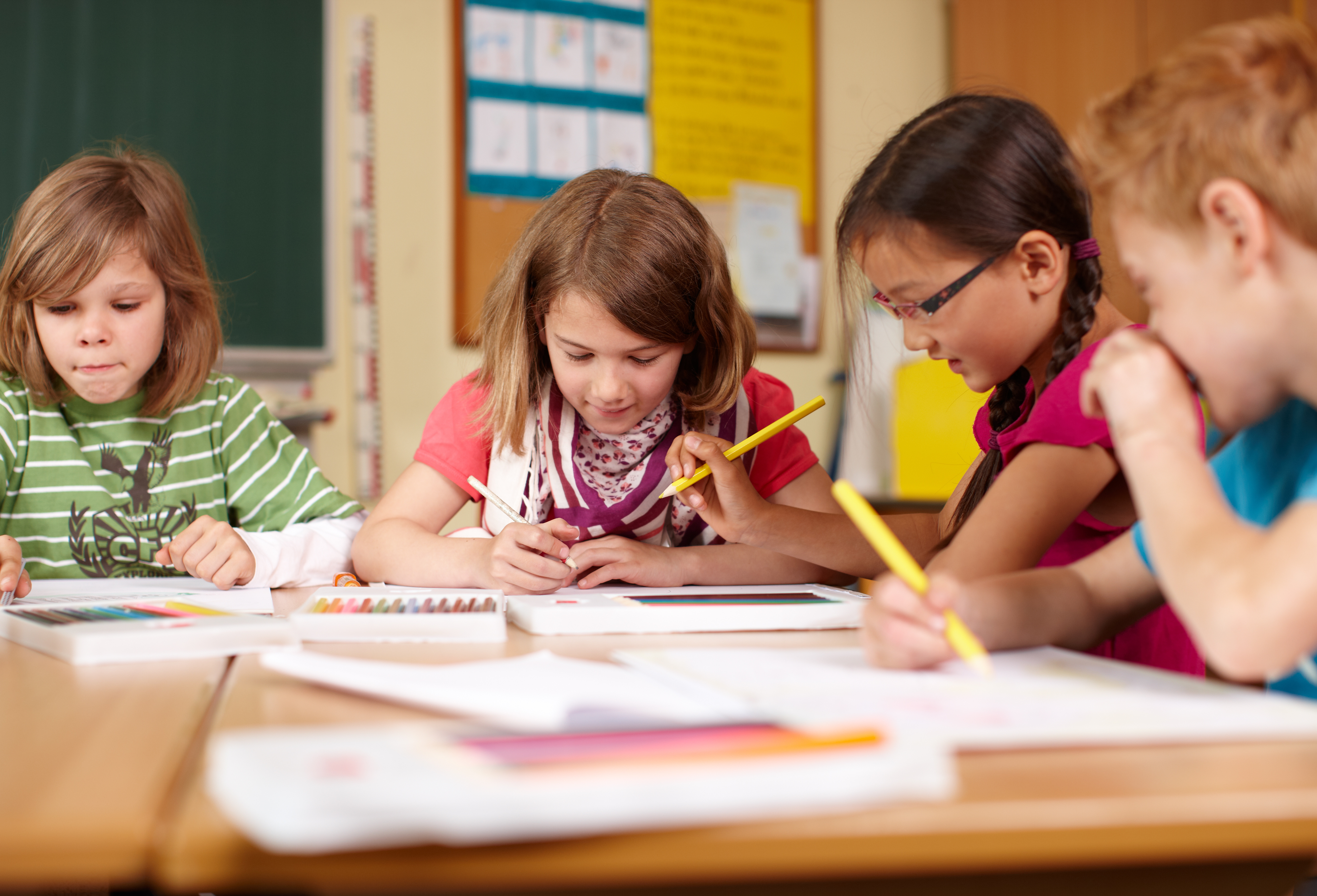 Vier Grundschulkinder sitzen in einem Klassenraum und lösen eine Aufgabe