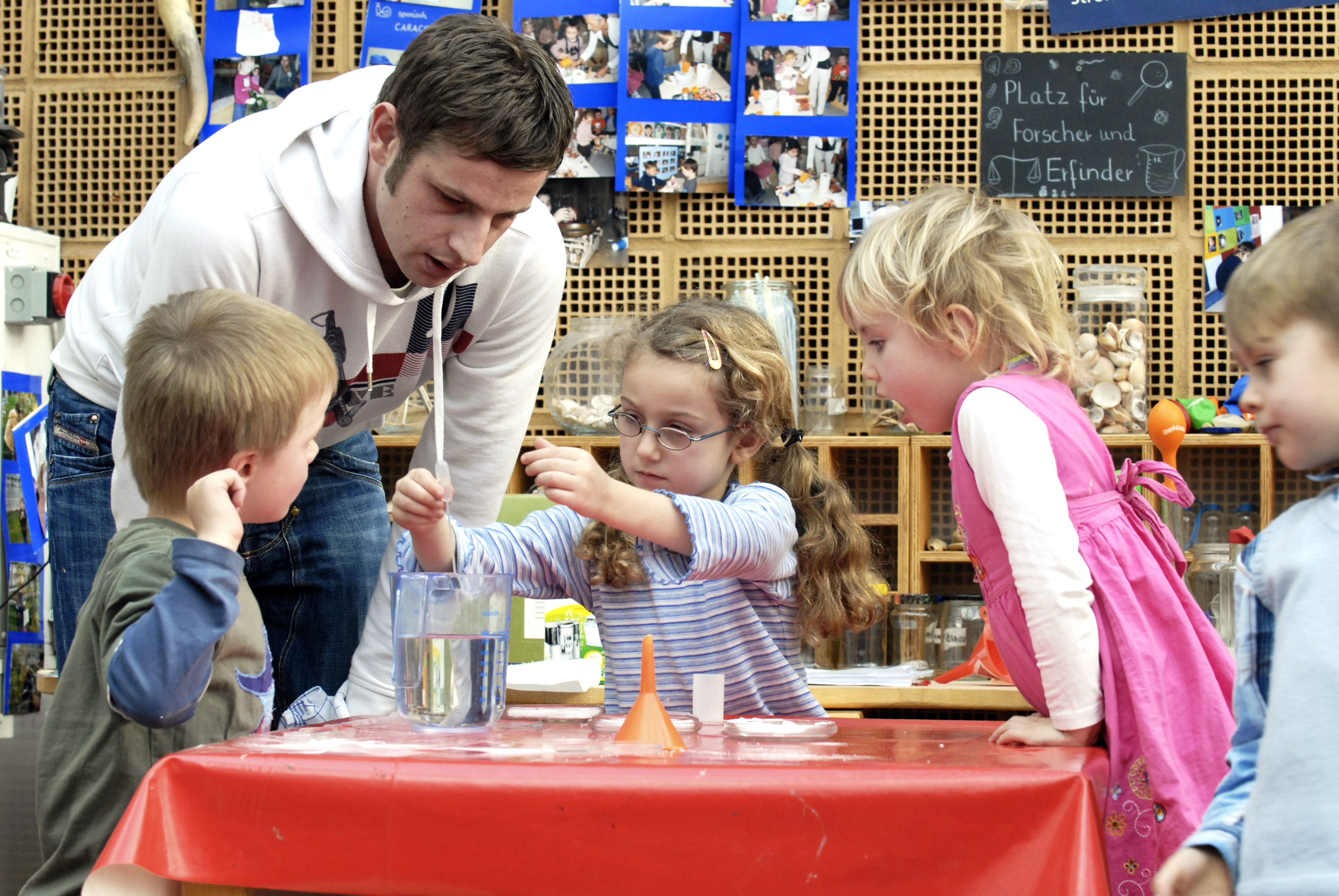 Kinder und ein Erzieher beim Experimentieren in der Kita