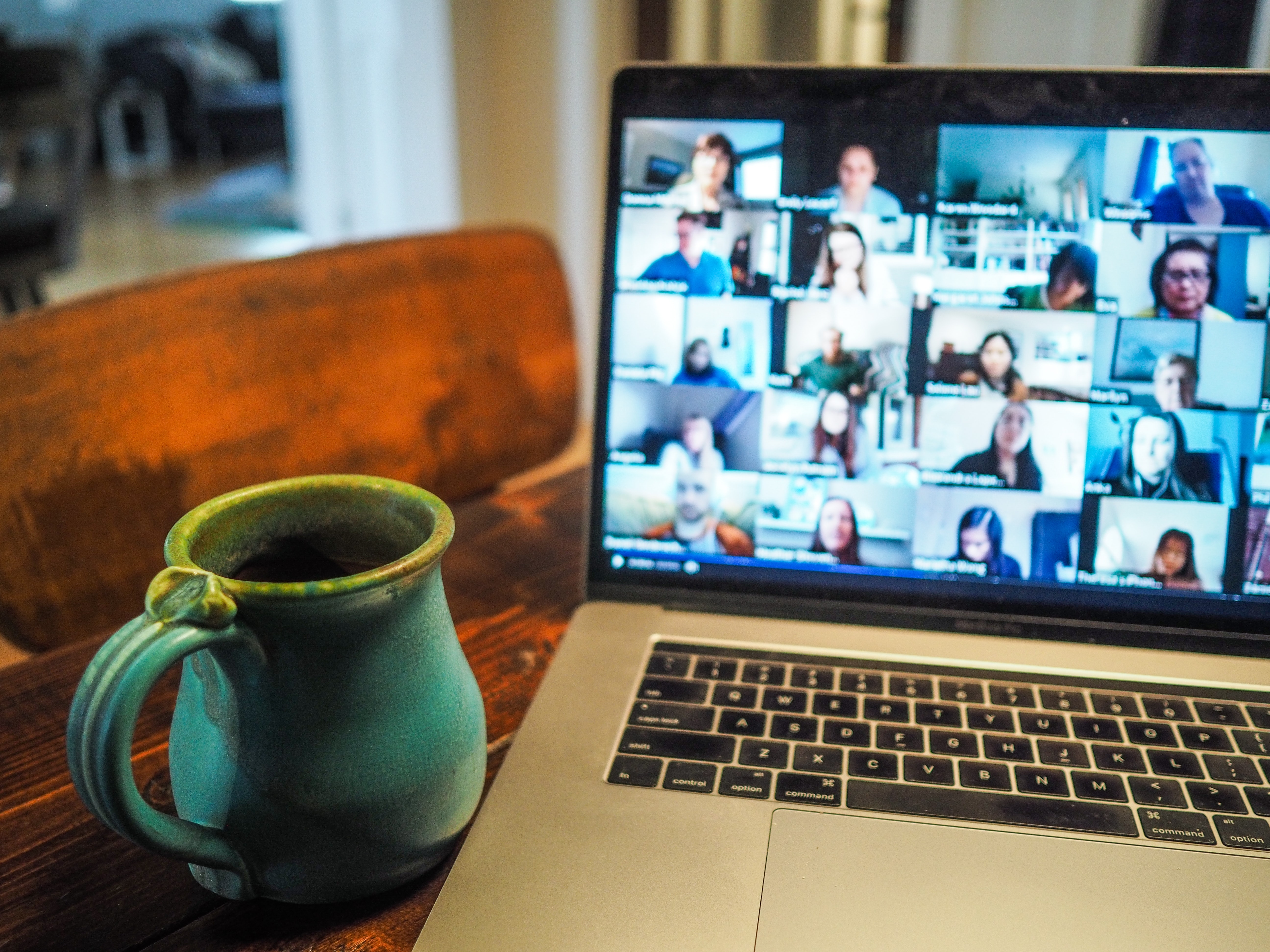 Blaue Tasse neben einem Laptop, während einer Videokonferenz