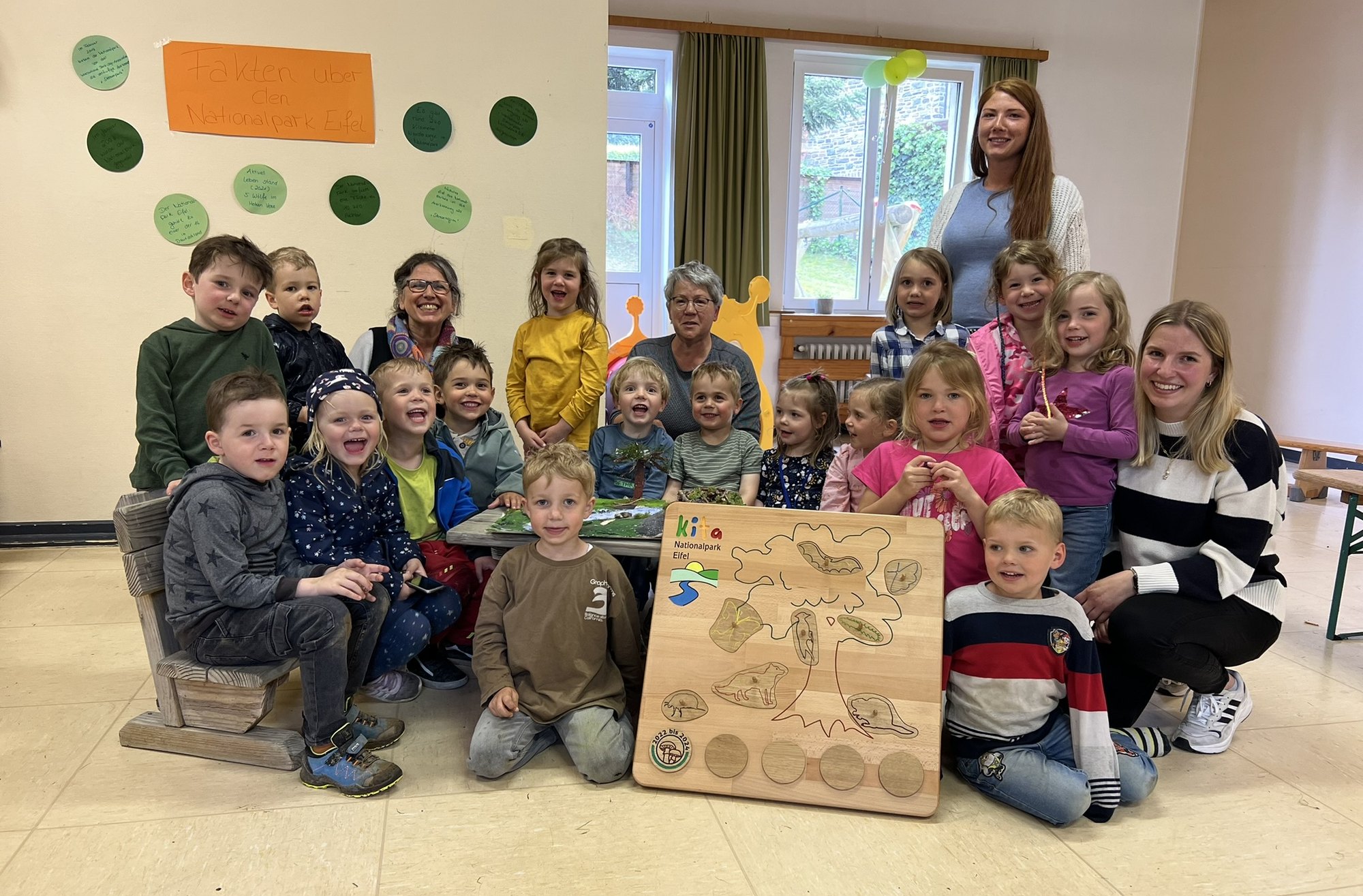 Kinder und Fachkräfte präsentieren Stolz das Zertifizierungsschild der Nationalpark-Kita