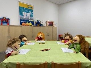 Handpuppen sitzen an einem Tisch und malen ein Bild